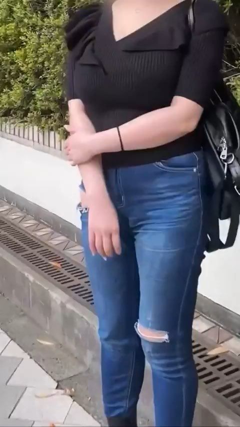 待ち合わせ場所に立つ私服姿の女性。黒のニットにデニム、リュックを背負っている